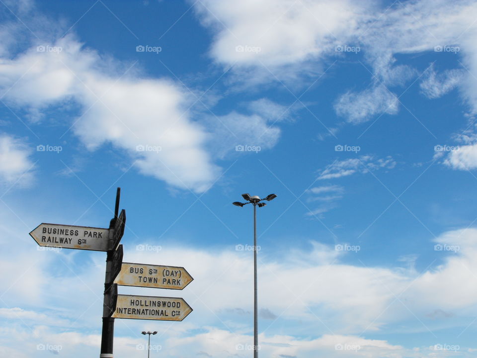Big beautiful sky with clouds, streetlights and directions