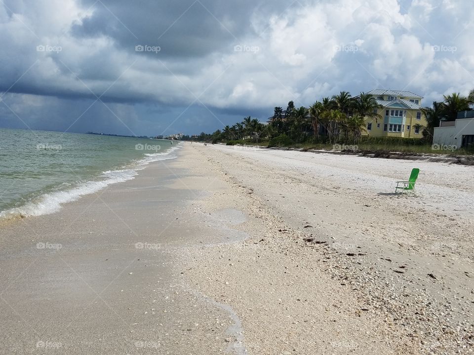 lonely chair on beach watching the storm roll in