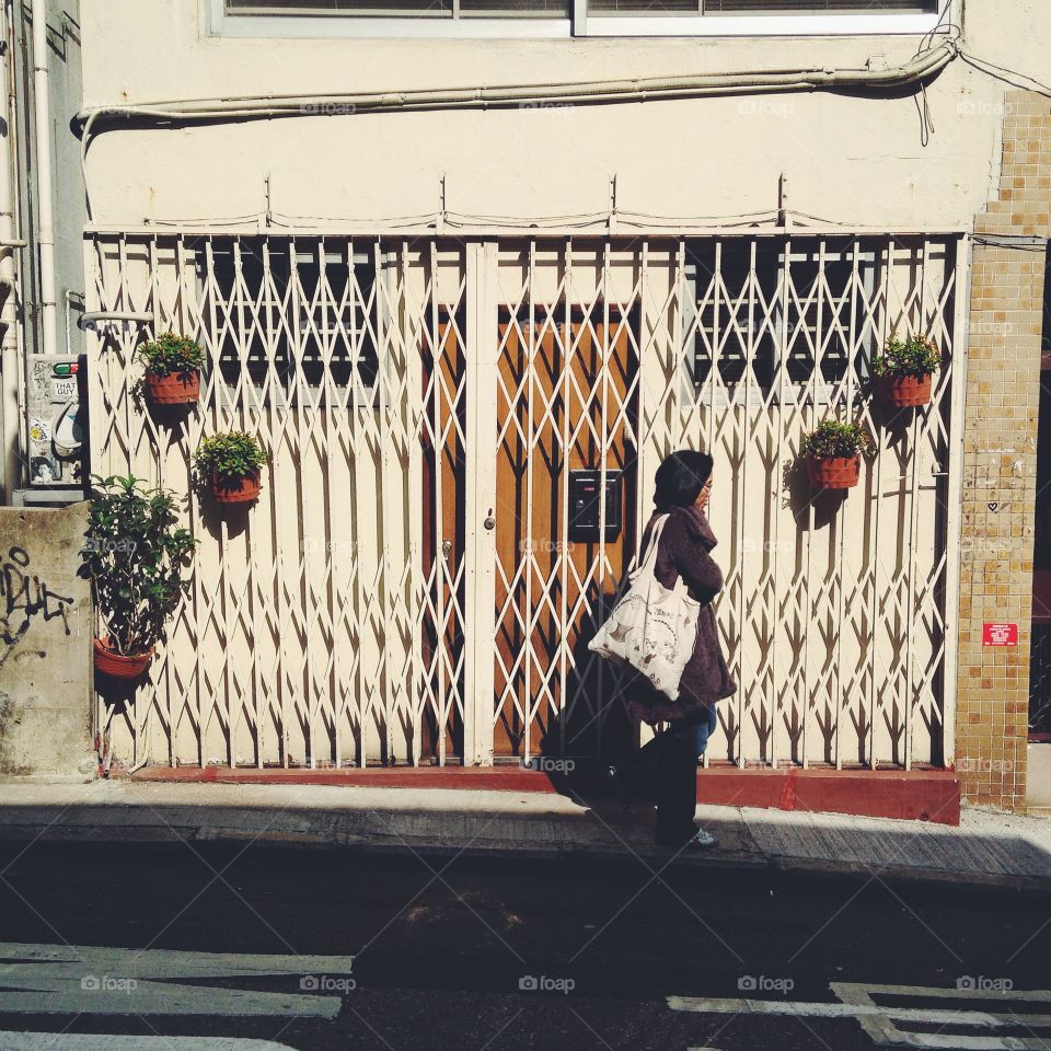 A woman walks past the front gate of a home in Sheung Wan, Hong Kong.