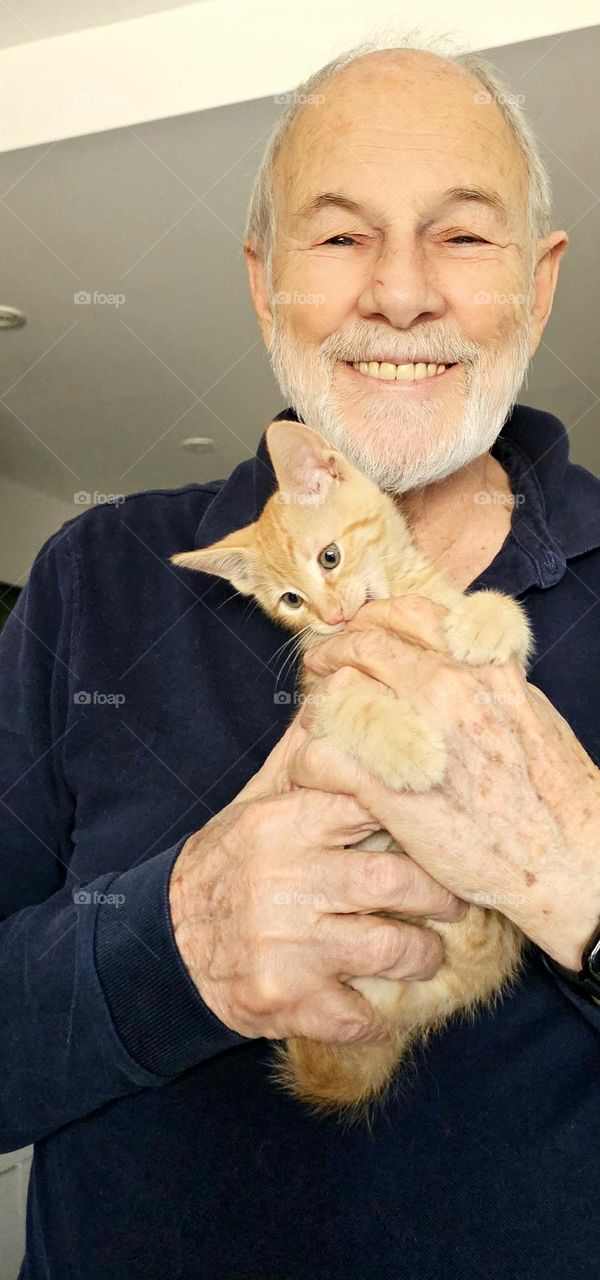 This man's happiness is in his loving hands.  He holds the kitten with affection and tender, loving care.