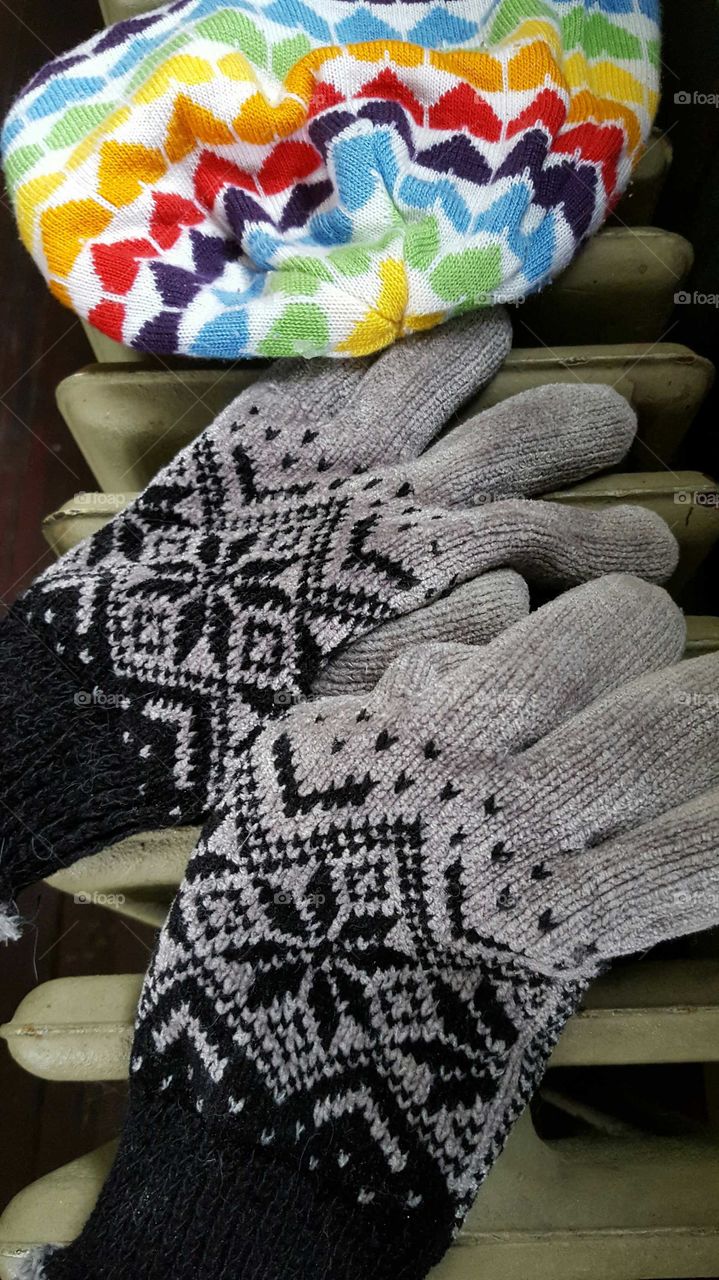 Winter hat and gloves drying on an old cast iron radiator after a day of fun in the snow.