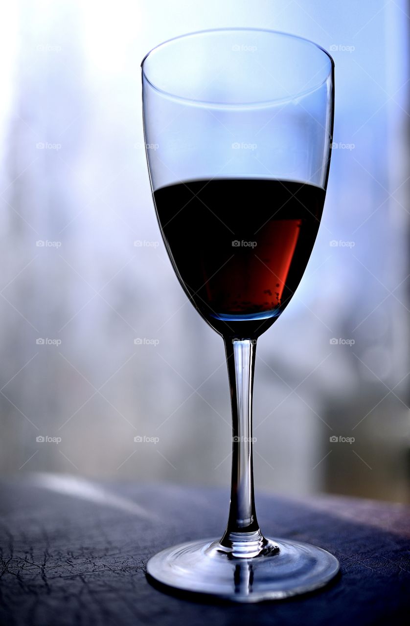 Close up shot of wine glass with the natural light for the background that shows the color of the wine.