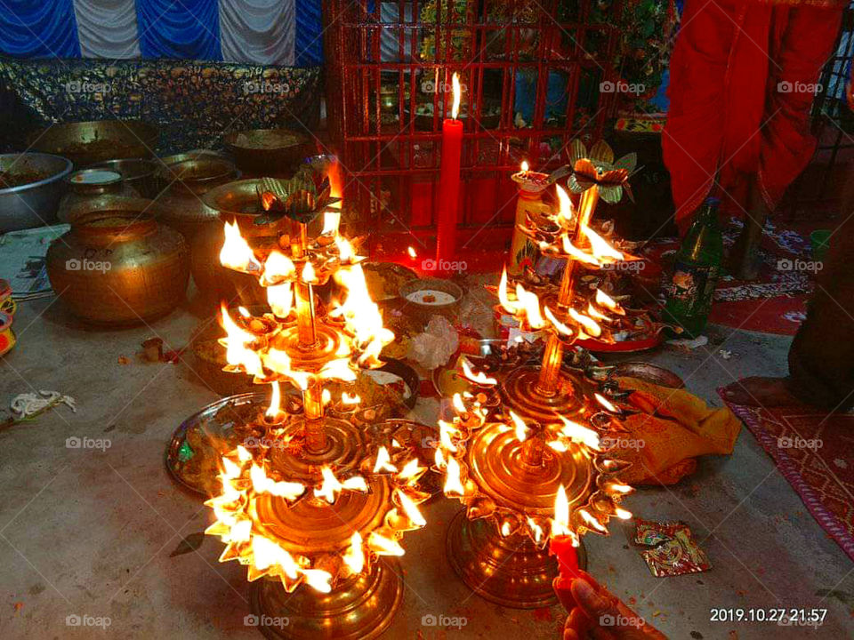 Closeup of Illuminated tall brass oillamps In Temple. People burning oil lamps as religious ritual in Hindu temple,India.