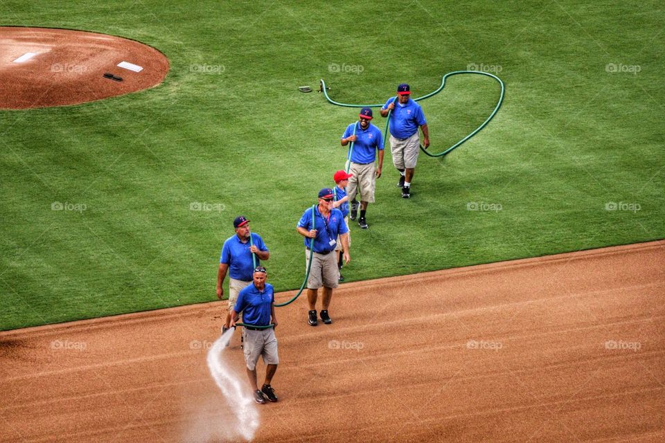 Field prep. Men spraying down the baseball field at globe life park in Arlington Texas before. Texas Rangers game