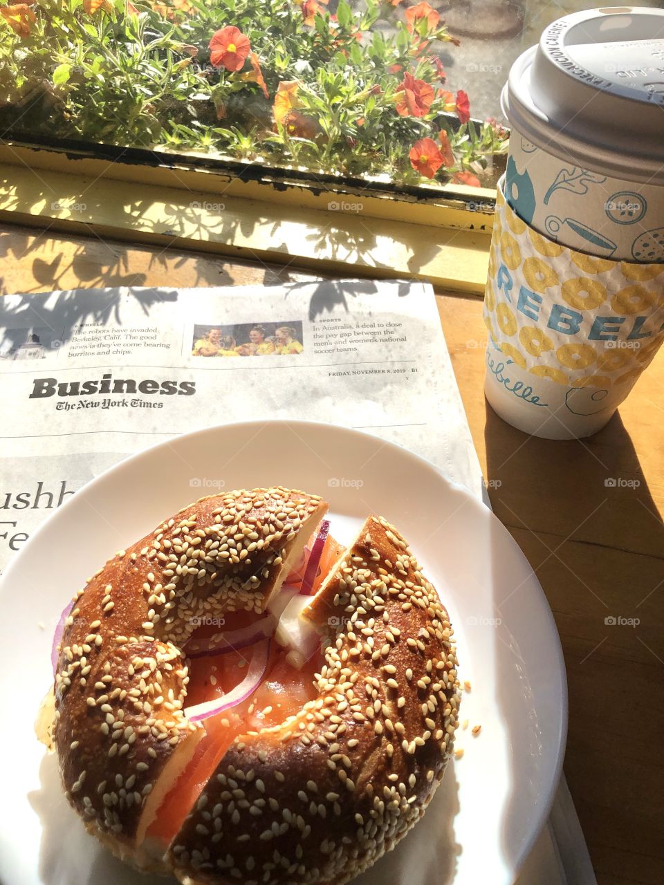 Breakfast, sesame bagel with sliced lox and coffee along with the morning paper