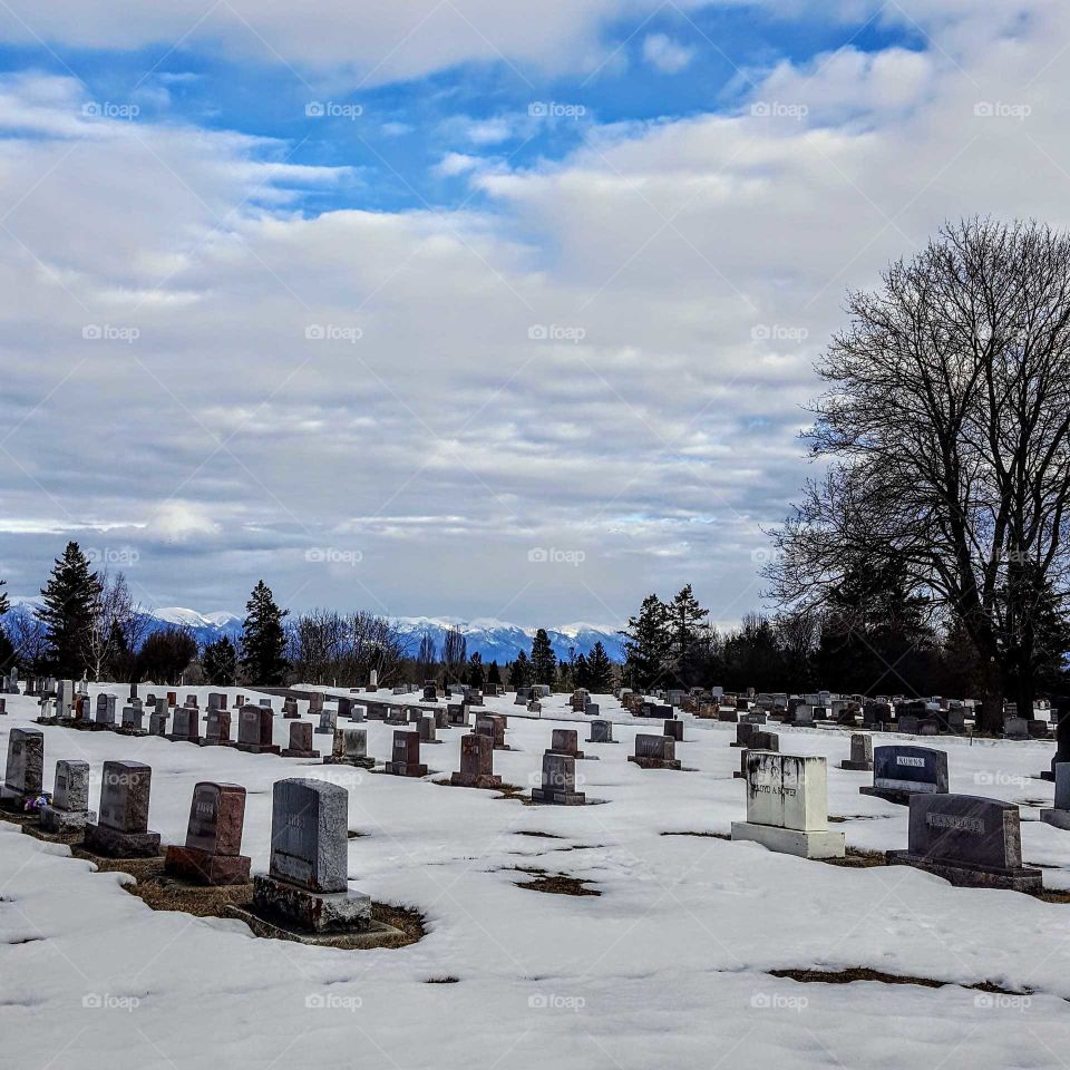 blue sky white clouds over snowy cemetery