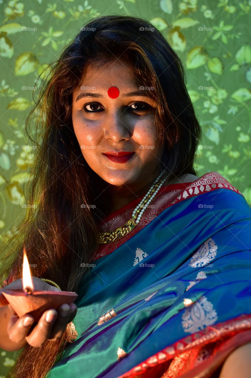 Indian woman taking selfie with diya in hand during Diwali festival