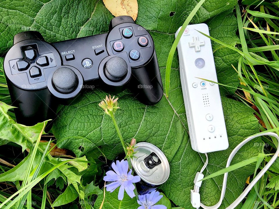 Different controllers for computer games and a can of drink.