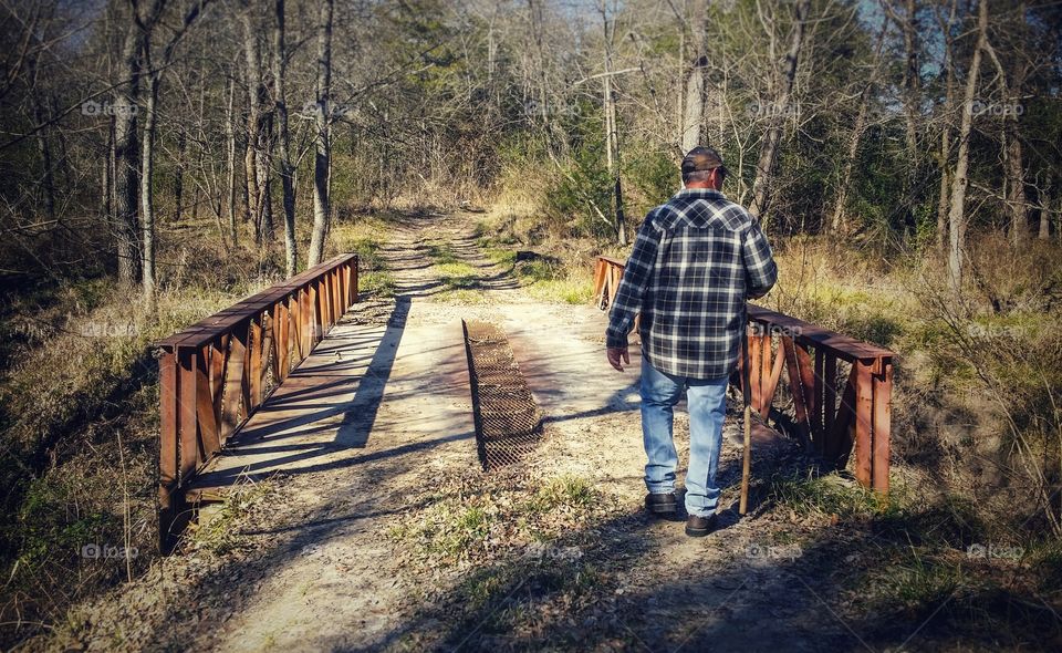 A man walking over a bridge in winter from a to b