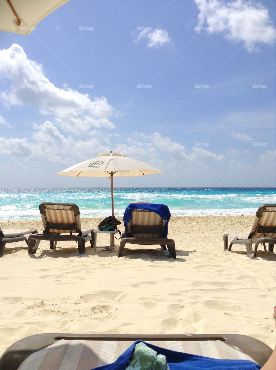 
view of the beach with white sand and blue sea, plush umbrellas and sun loungers.