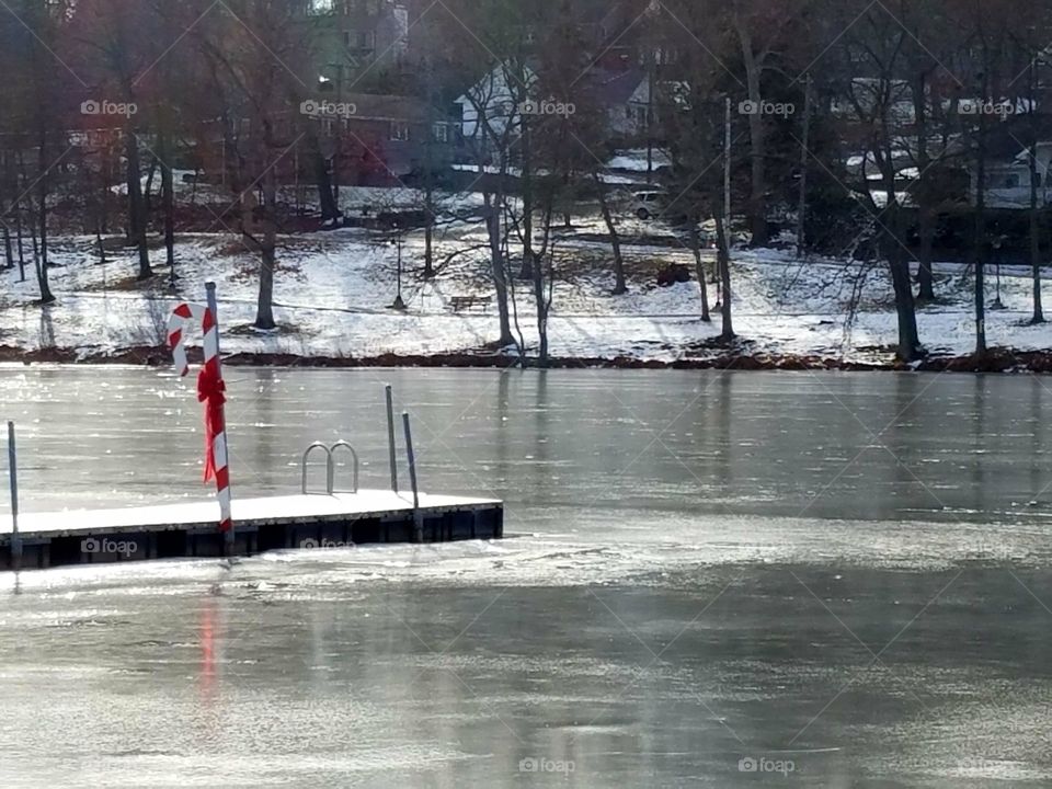 Candy cane decoration on a dock in a frozen lake