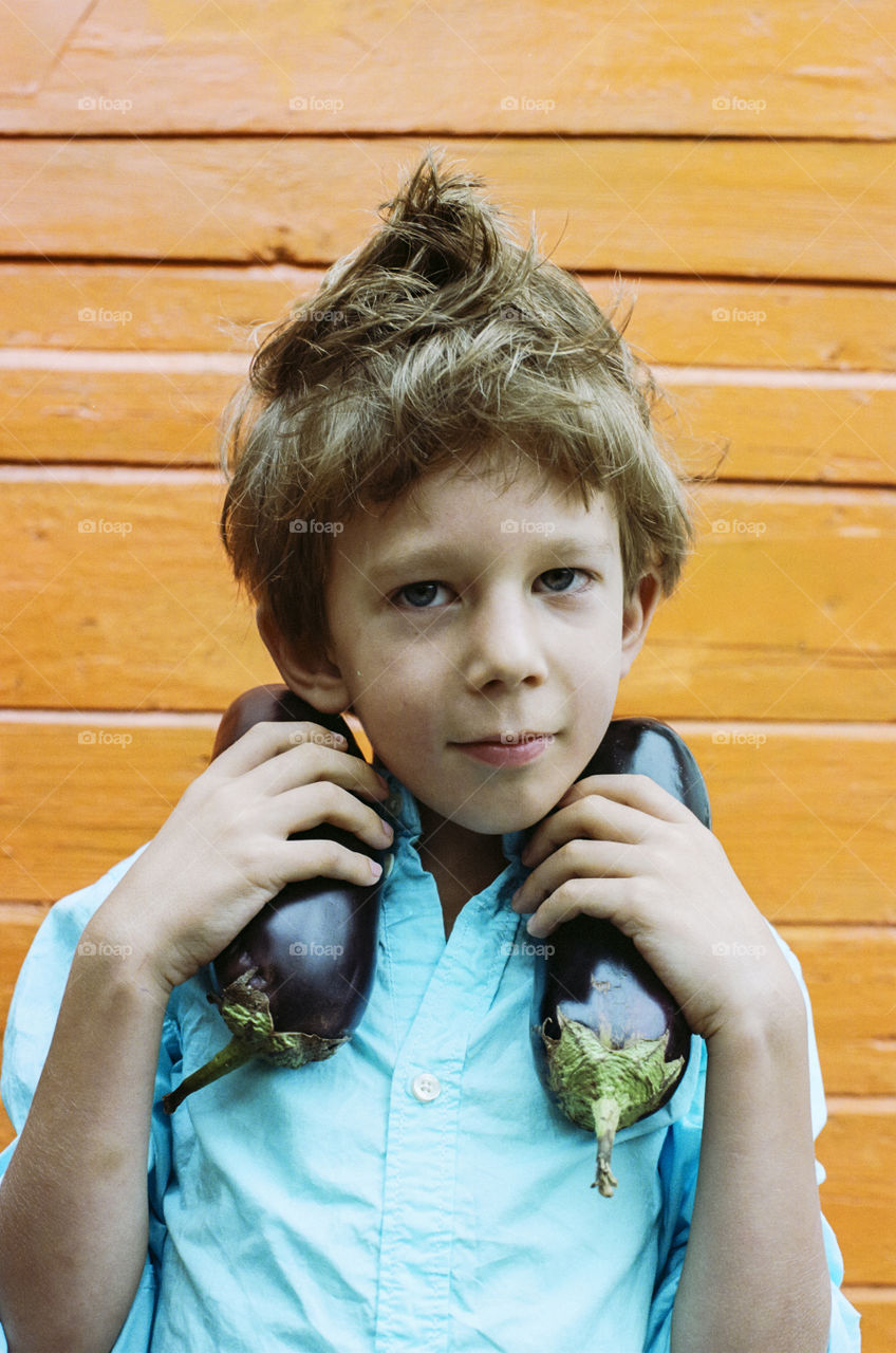 Close-up of a boy holding eggplant in hand