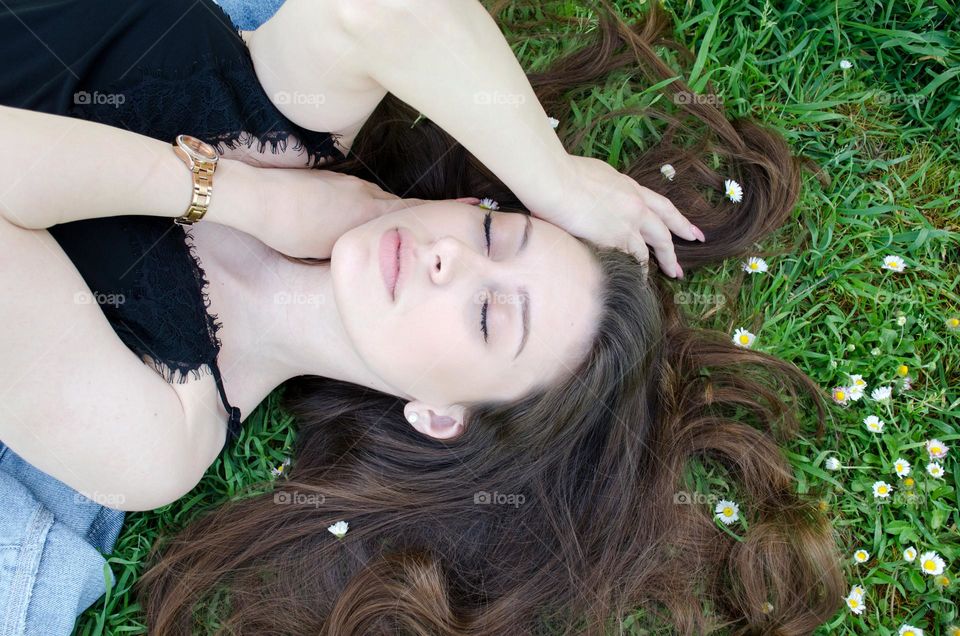 Portrait of Beautiful Young Girl on Background of Daisies