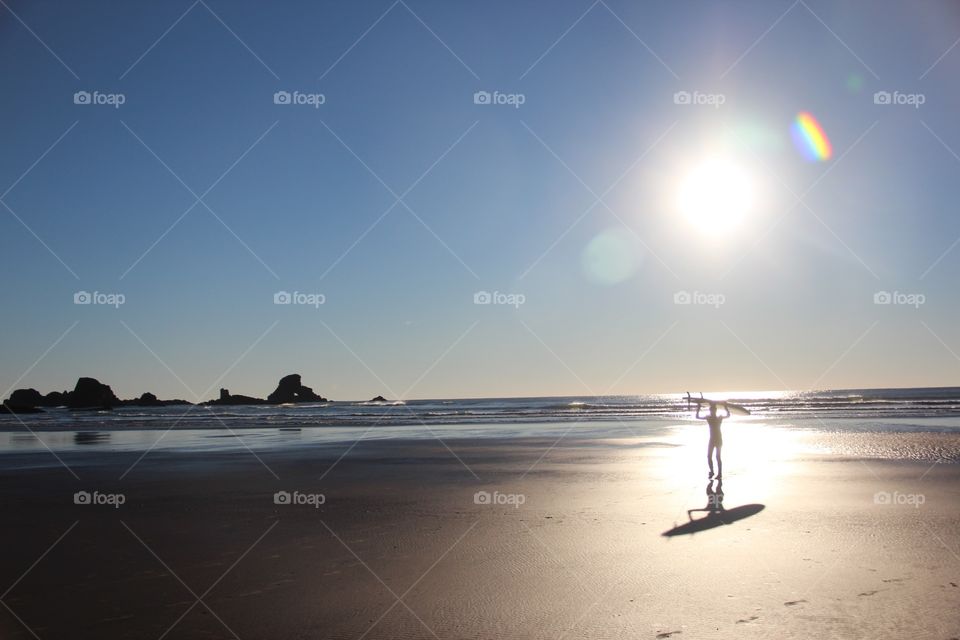 Solitude of person carrying surfboard at beach