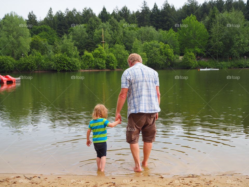 Grandfather and granddaughter paddling in a lake