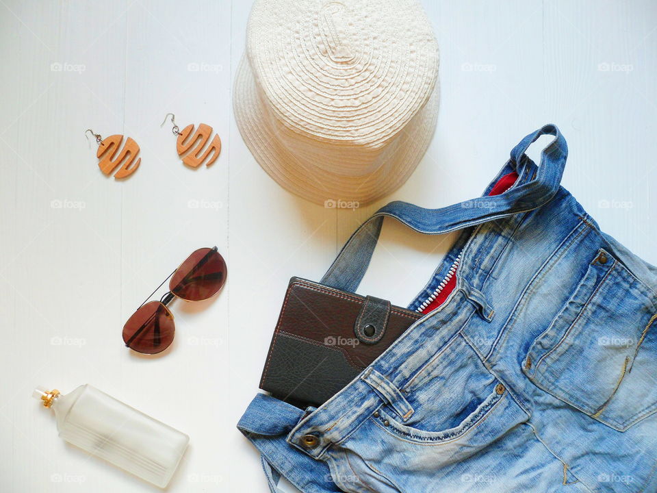 jeans bag, hat sunglasses, notebook, eau de toilette and earrings on a white background