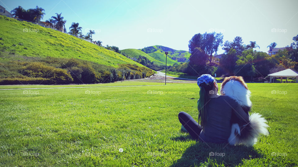 Dog and woman looking at the view, sitting side by side at the park, man's bestfriend