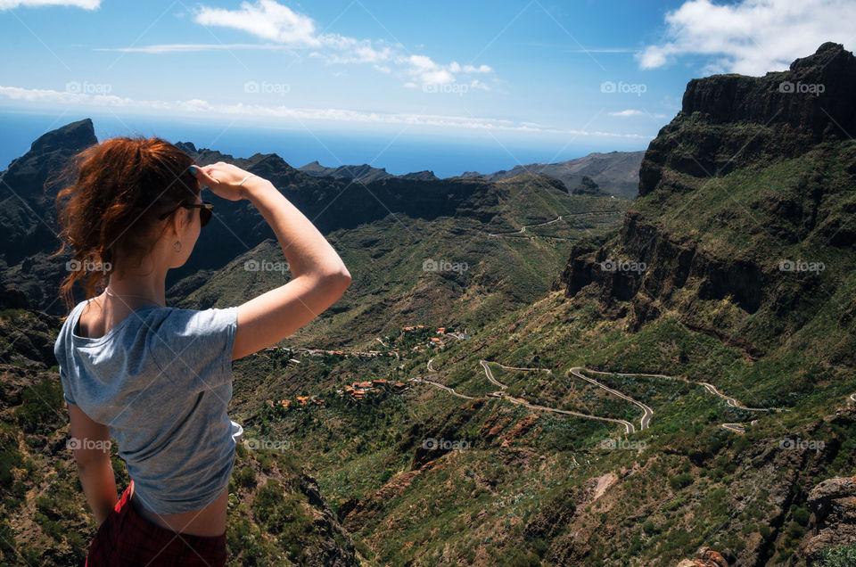 Young woman stands back to the camera and looks at the valley, Masca, Tenerife, Canary Islands, Spain