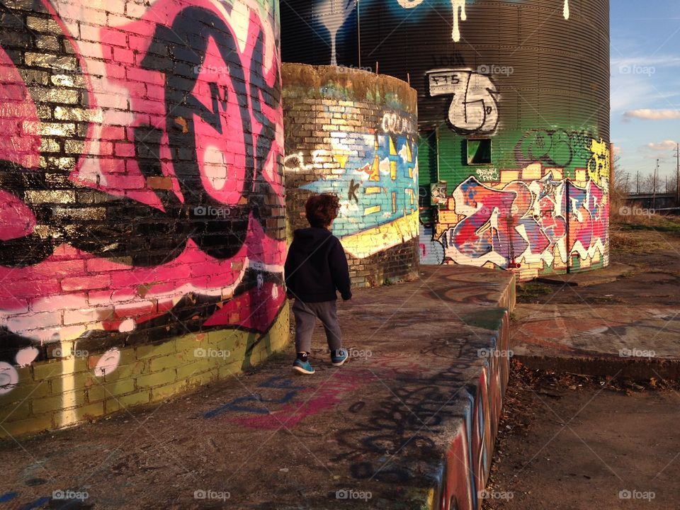 A boy walking in front of graffiti in the river arts district in Asheville, NC