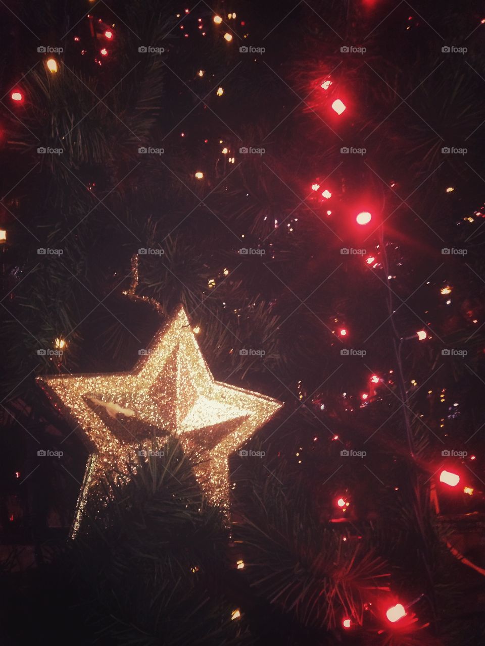 Gold plastic star, balls, red lights garland and other Christmas decorations on artificial fir tree in Moscow, Russia