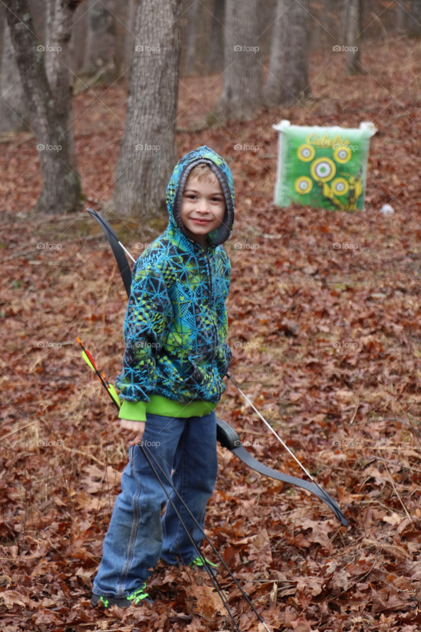 Cute boy holding bow and arrow in the forest
