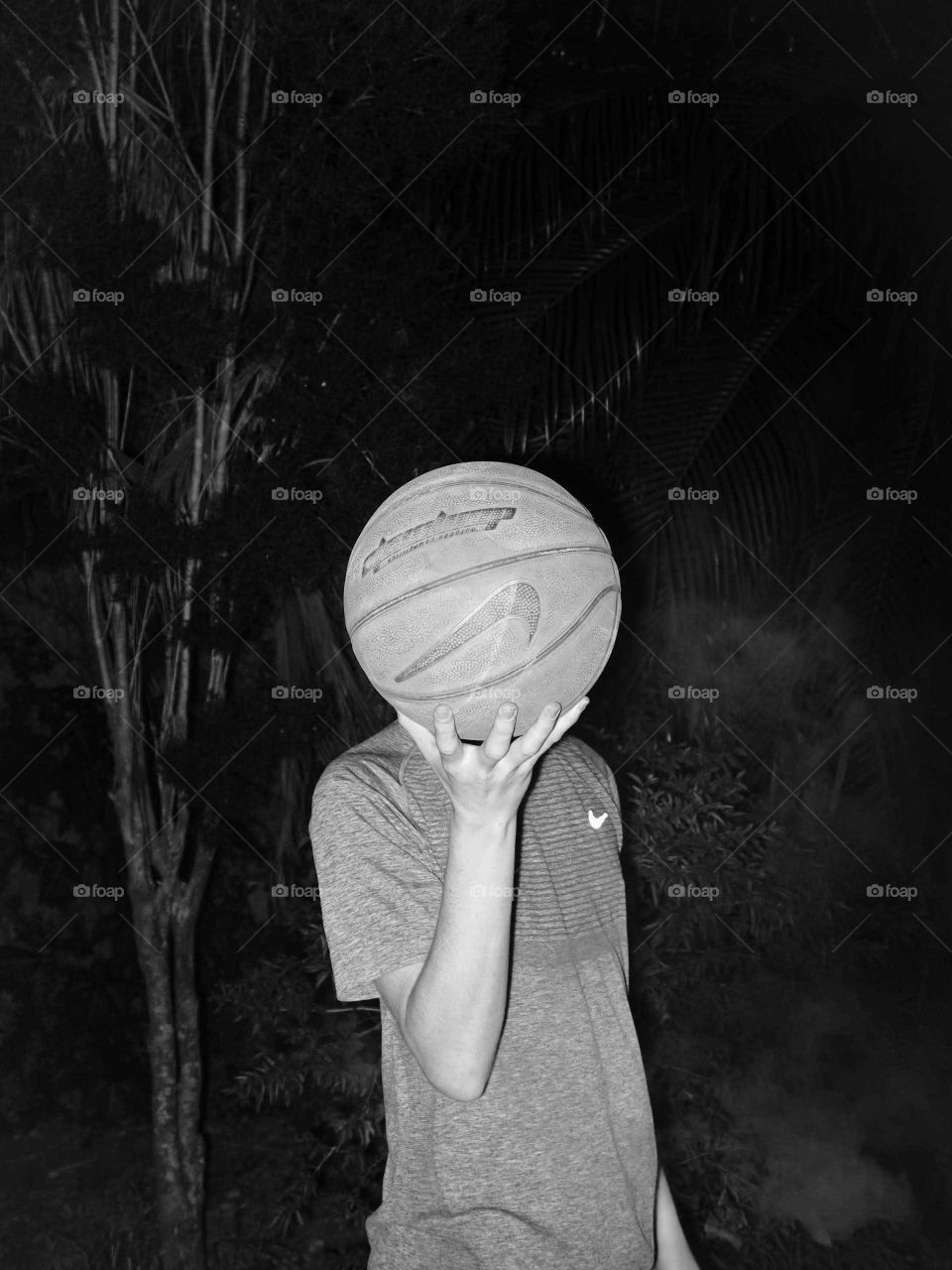 Man holding his basketball head, black and white trippy and surreal portrait.