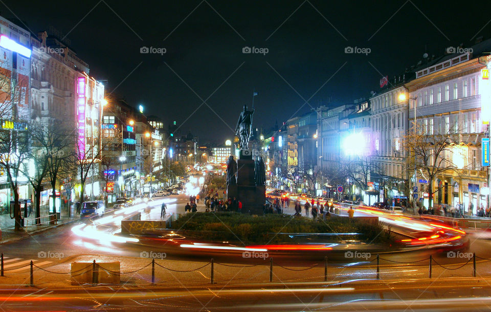 Wenceslas square with long traffic lights late autumn evening by Museum of cockroaches with a focus on monument Wenceslaus. People whose faces cannot recognize, going to the circle and having fun.