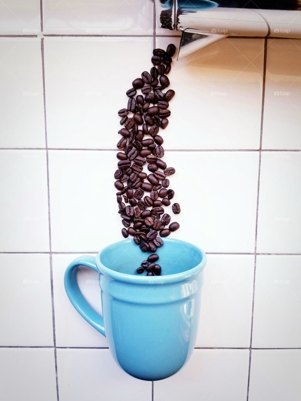 Coffee Beans Being Poured into a Blue Mug from a pot