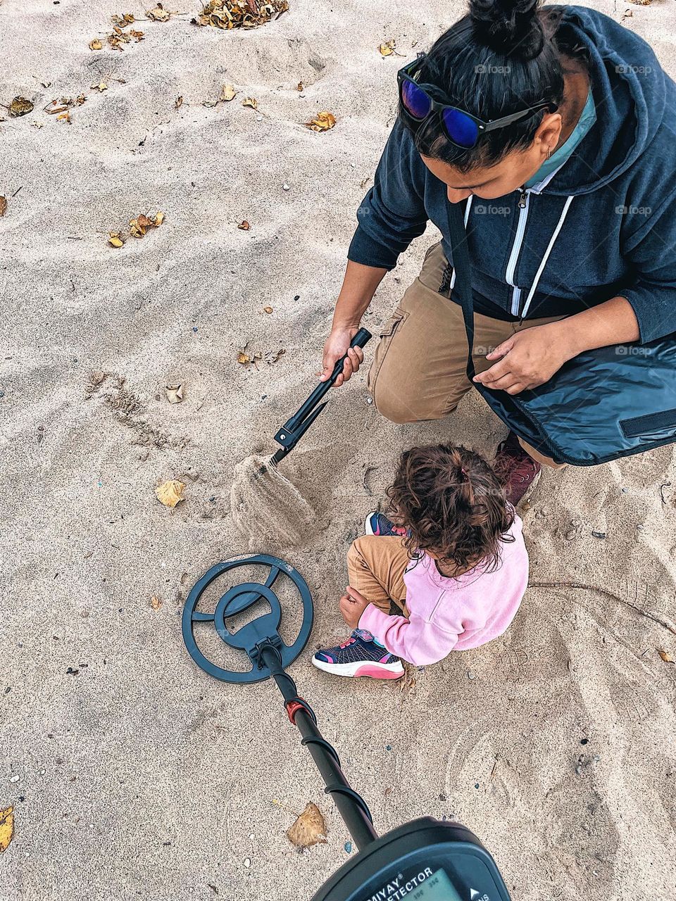 Family searching for treasure on the beach, family time at the beach, using a metal detector at the beach, family searching for treasure, family digging in the sand, family treasure hunt, vacation activities for the beach 