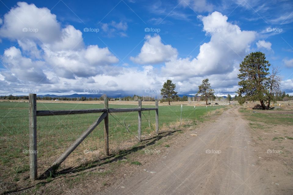 Farm road under the big sky full of clouds in Bend, OR
