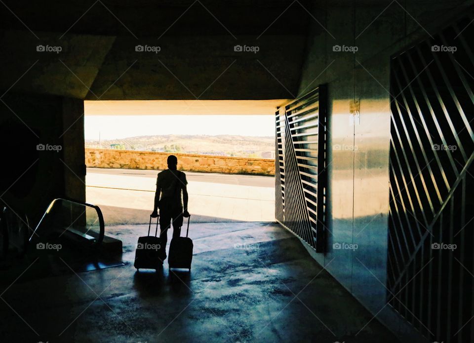 Man going away with luggage towards landscape