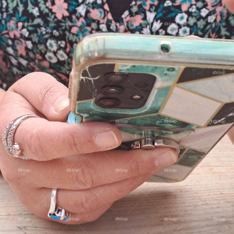 young ladies hand with rings holding and using her mobile phone