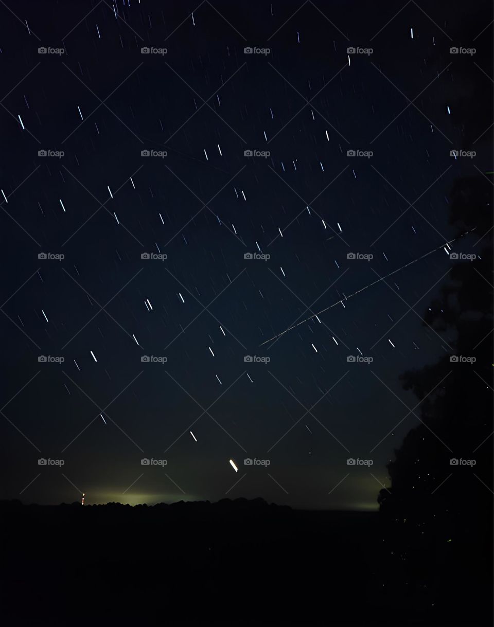 This is a long exposure star trail with Venus as the main character. You will see Venus as the trail closest to the horizon setting. Also, notice the space satellite trail coming in from the right.