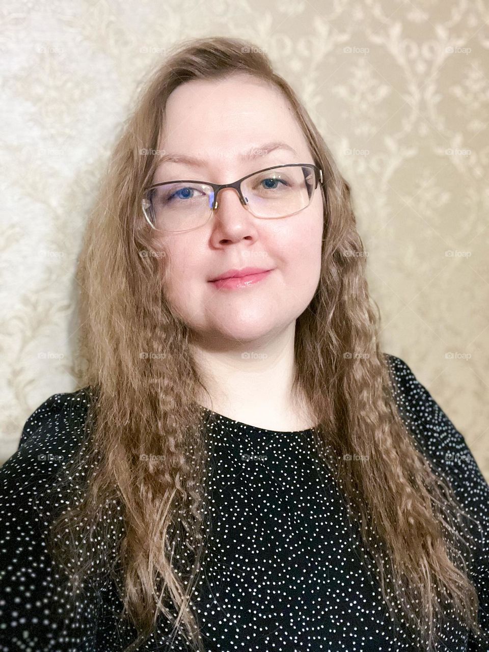 Woman is smiling in black dress with white polka dots