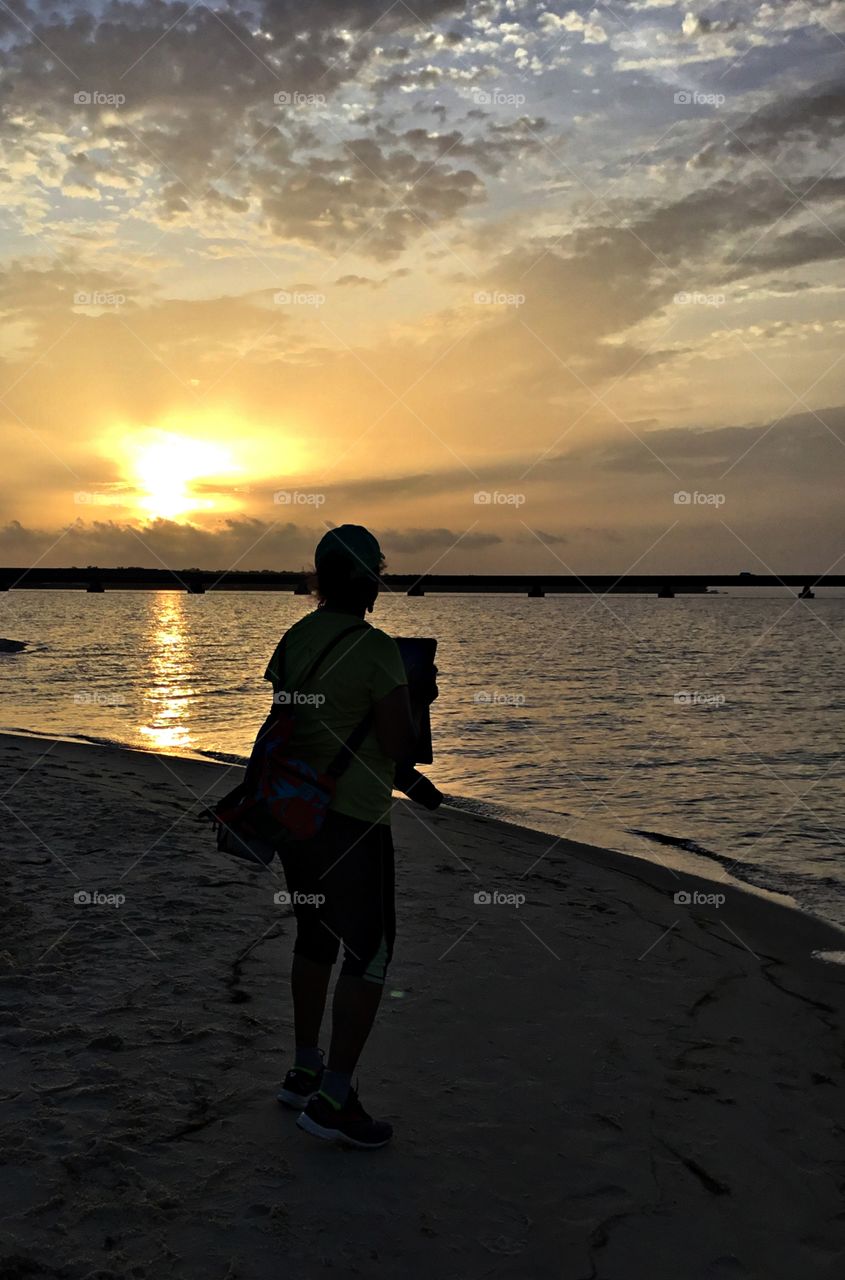 
Each day is born with a sunrise and ends in a sunset. A young women takes a morning walk on the sandy beach during sunrise