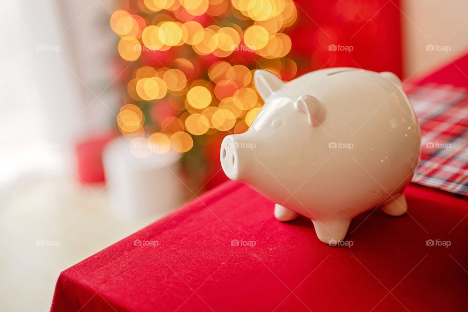 piggy bank with 100 dollars banknote in festive New Year atmosphere of scenery.  Magical bokeh with Christmas tree and bright lights.