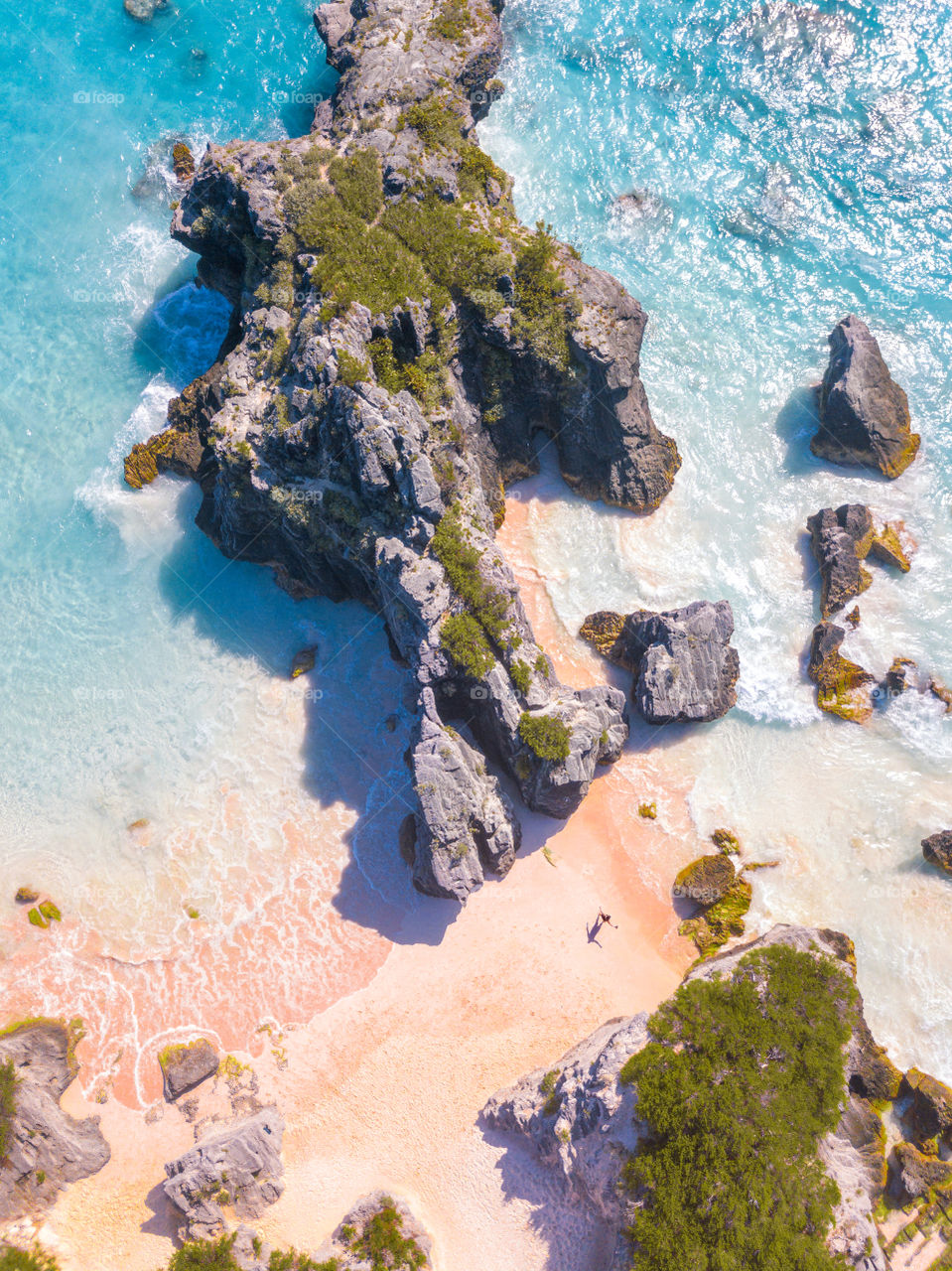 Top down view of tropical summer vibes with crystal clear blue water and a pristine sandy beach. Silhouette of a person on the beach enjoy the beautiful location.