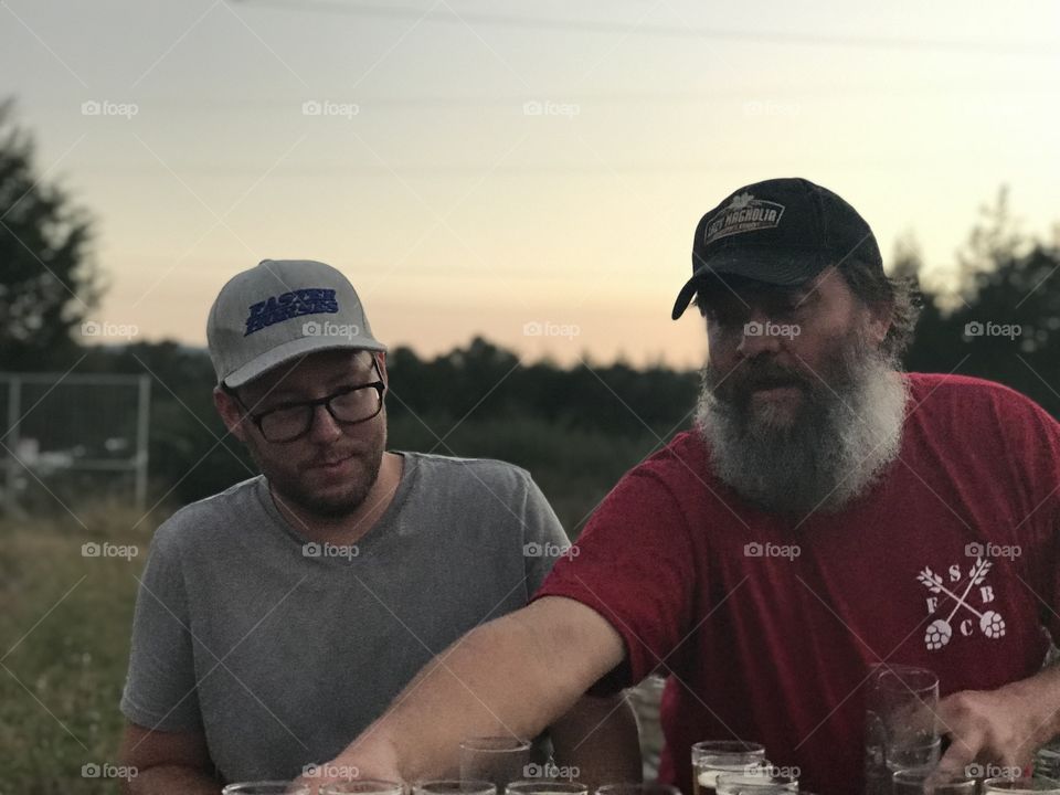Dusk at a small farm in subiaco, Arkansas. Owner presenting customer with craft beer grown and brewed at their farm.