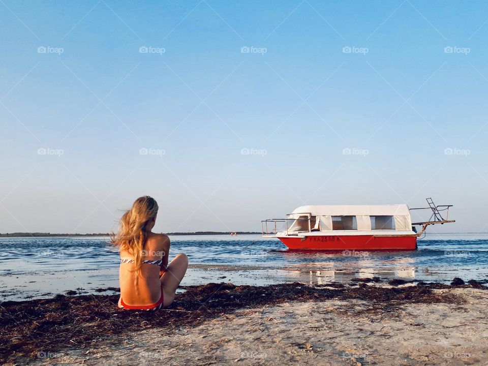 Faceless woman on the beach with boat