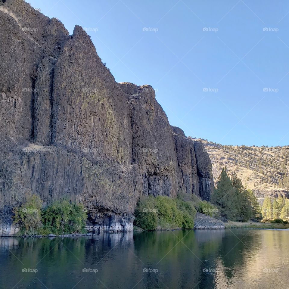 The beautiful Crooked River with fall colored bushes on its banks flows through a canyon formed from andesite and basalt flows on a nice autumn evening in Central Oregon. 