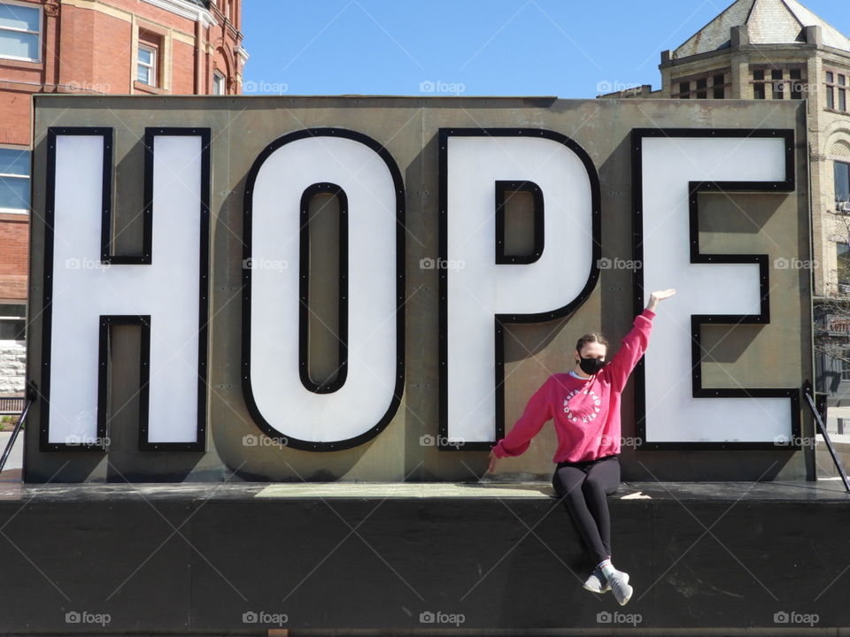 young woman in front of hope sign during pandemic