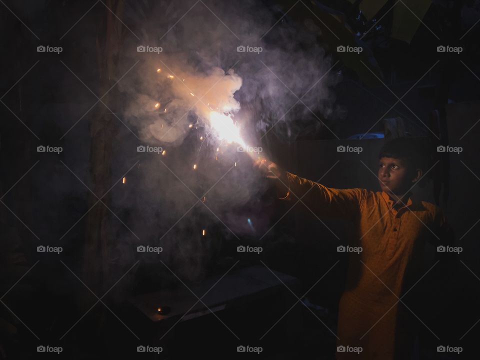 Boy celebrating Diwali with a firecracker 