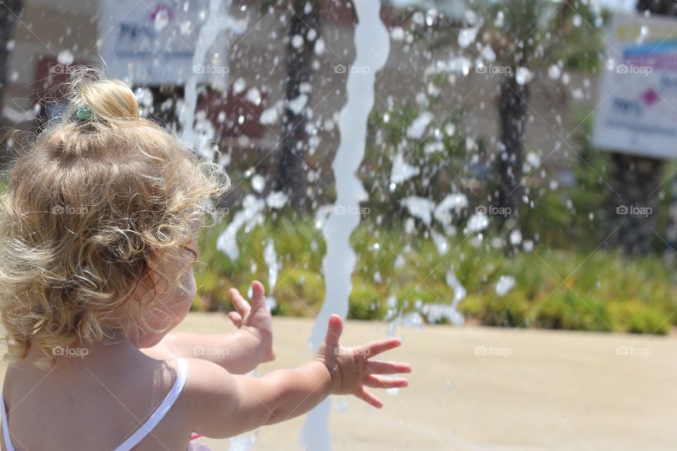 Rear view of a girl standing in front of water fountain