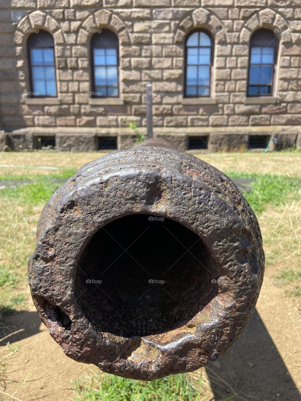 A cannon outside the Twin Lights State Historic Site in Highands, NJ. The building in the background has lighthouses on either side with a museum in between outlining the history of the historic site. 