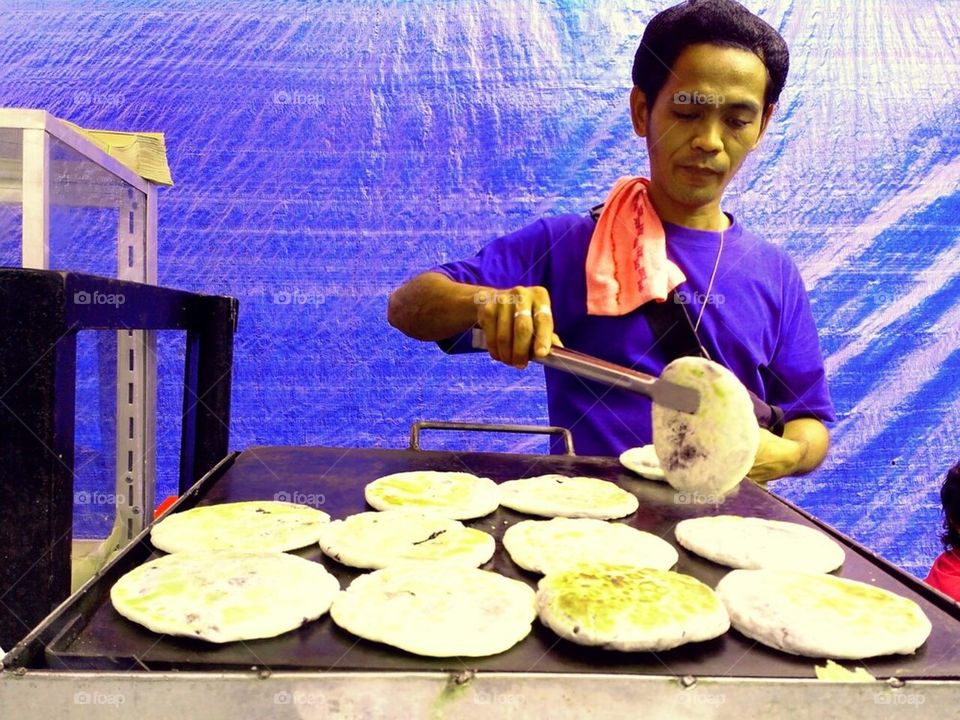 Asian man cooking sweet bread and sold as street food