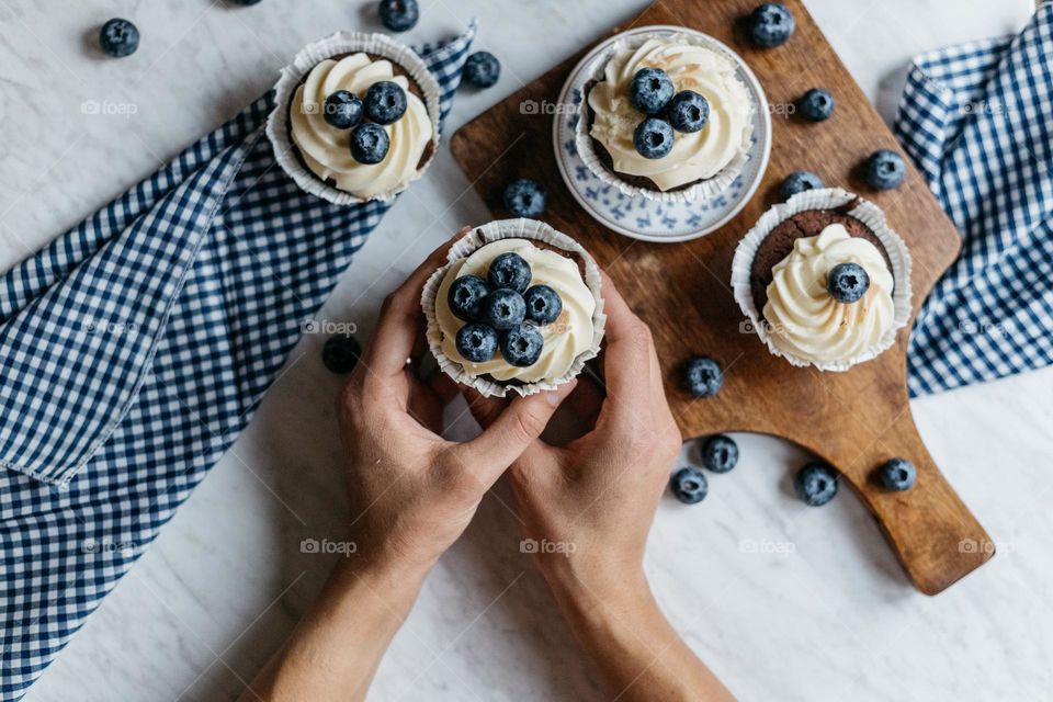 Woman holding a delicious homemade cupcake with blueberries.