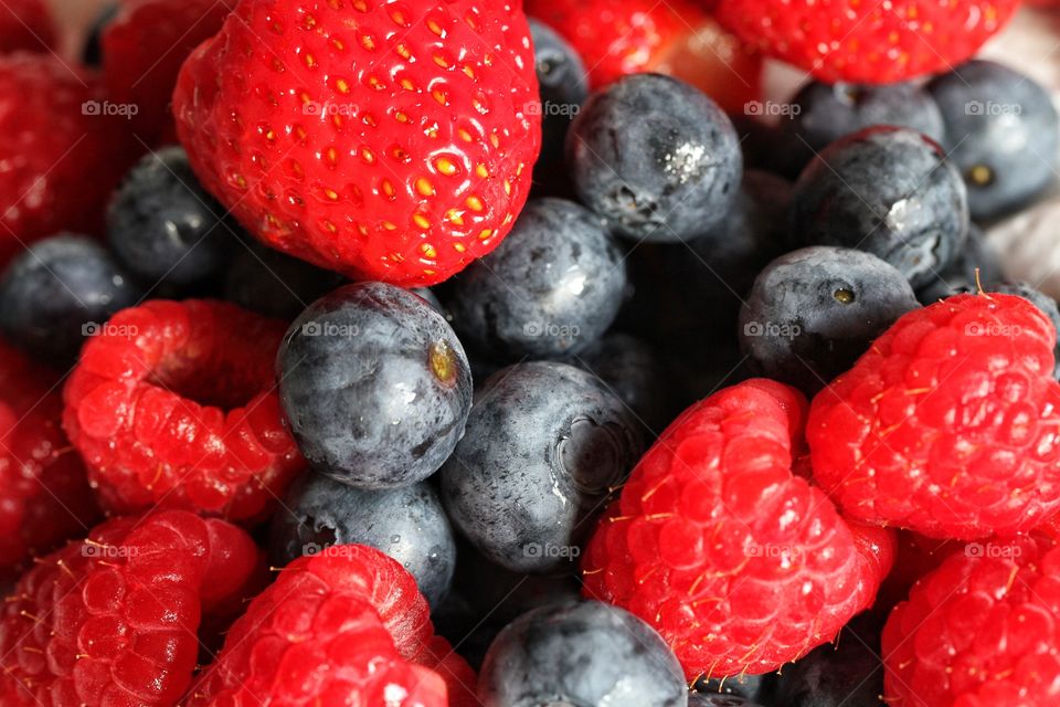 A frame full of ripe, juicy raspberries and blueberries.