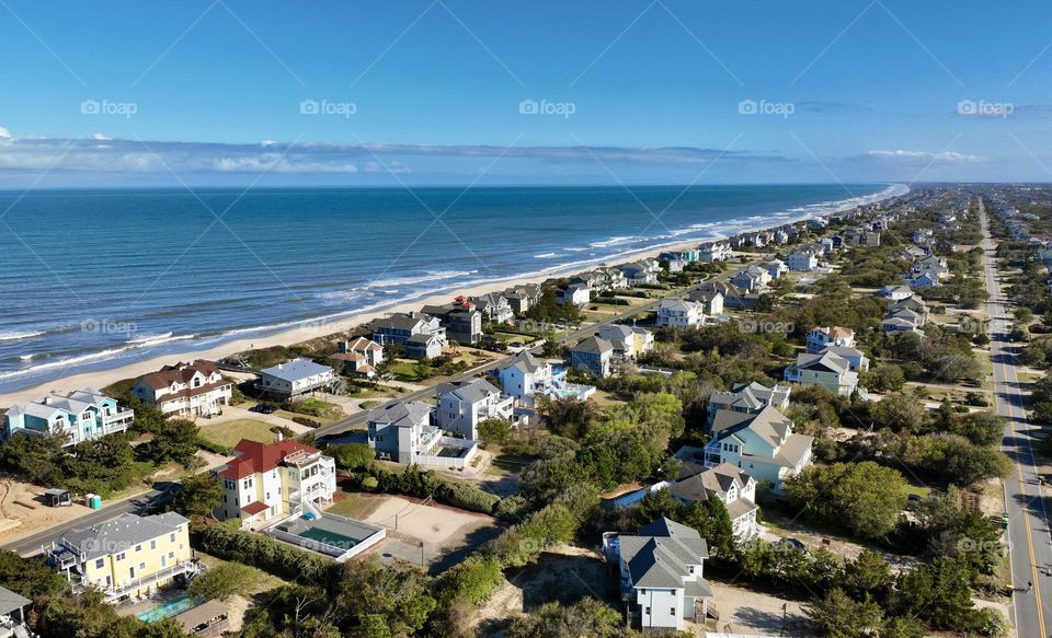 From high above duck, North Carolina presents a breathtaking panorama. The sun has warm glow over the beach with beautiful hues of colors in the homes shores.