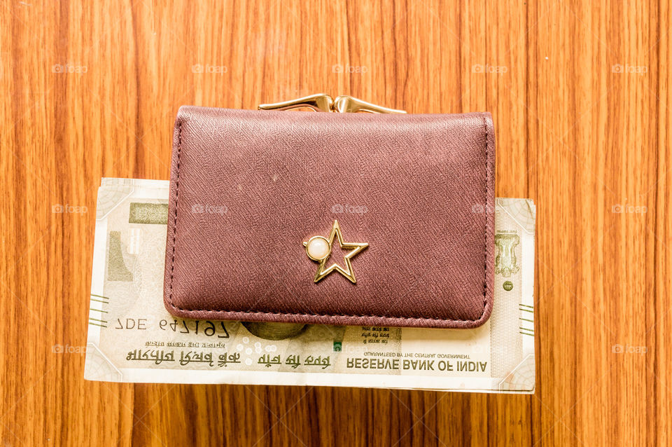 Indian five hundred (500) rupee cash note in brown color wallet leather purse on a wooden table. Business finance economy concept. High angel view with copy space room for text on top side of image.