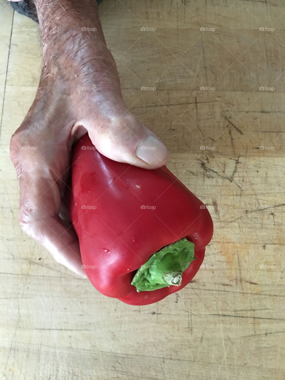 Hand holding uncut red pepper 